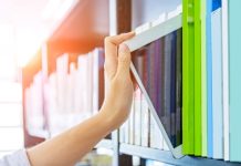 Vrouw pakt tussen de boeken in de boekenkast een tablet