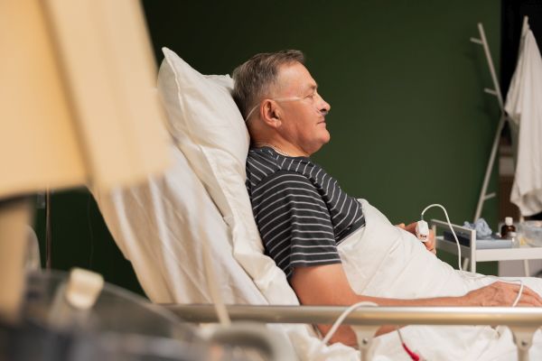 Hospitalized senior with oxygen tube, fingertip monitor, fatigue evident likely recovering from a respiratory illness
