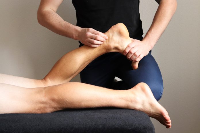 Masseur does sports legs massage in spa center. Massage of myofascial trigger points on leg of male client to release tension. Rehabilitation, sport therapy medicine.