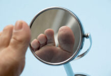 Huidveranderingen signaal voor slecht gereguleerde diabetes Person looking at the sole of the foot in a mirror, to check if there is no diabetic foot, as possible sores